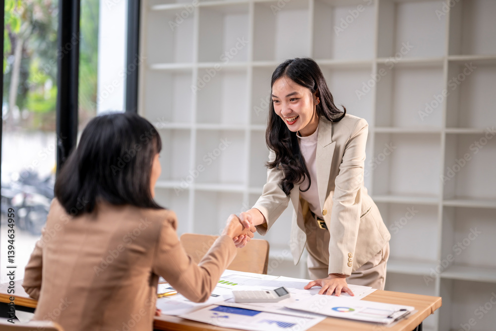 Two women shaking hands in a business setting Two women shaking hands in a business setting