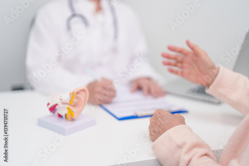 Elderly Patient consulting Doctor to Ear disease. Senior Health Medical Diagnosis. Anatomy Ear model for Atresia, Otitis Media, Pertorated Eardrum, Meniere syndrome, otolaryngologist, Hearing Loss photo