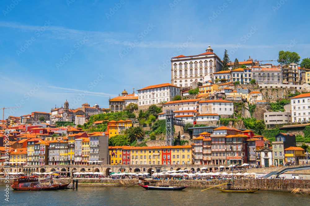 Cityscape of Porto (Oporto) over Douro River during a sunny day, Portugal. View of downtown Ribeira and embankment of Porto. Promenade view with colorful houses. Cityscape of Porto (Oporto) over Douro River during a sunny day, Portugal. View of downtown Ribeira and embankment of Porto. Promenade view with colorful houses.
