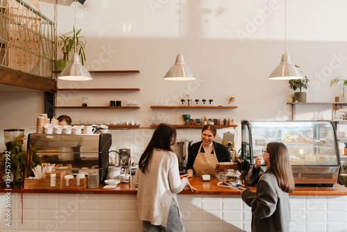 A White, overweight female barista aged 25, taking the order from two women in their late 20s, with a wide smile on her face, as she stands behind the counter in a cozy coffee shop