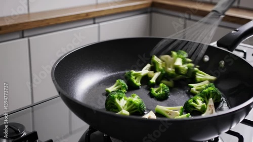 Cooking fresh broccoli in non-stick pan healthy meal preparation closeup