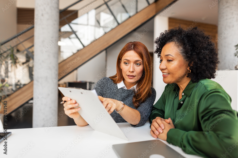 Obraz premium Two Professional Women Collaborating in a Modern Office Environment