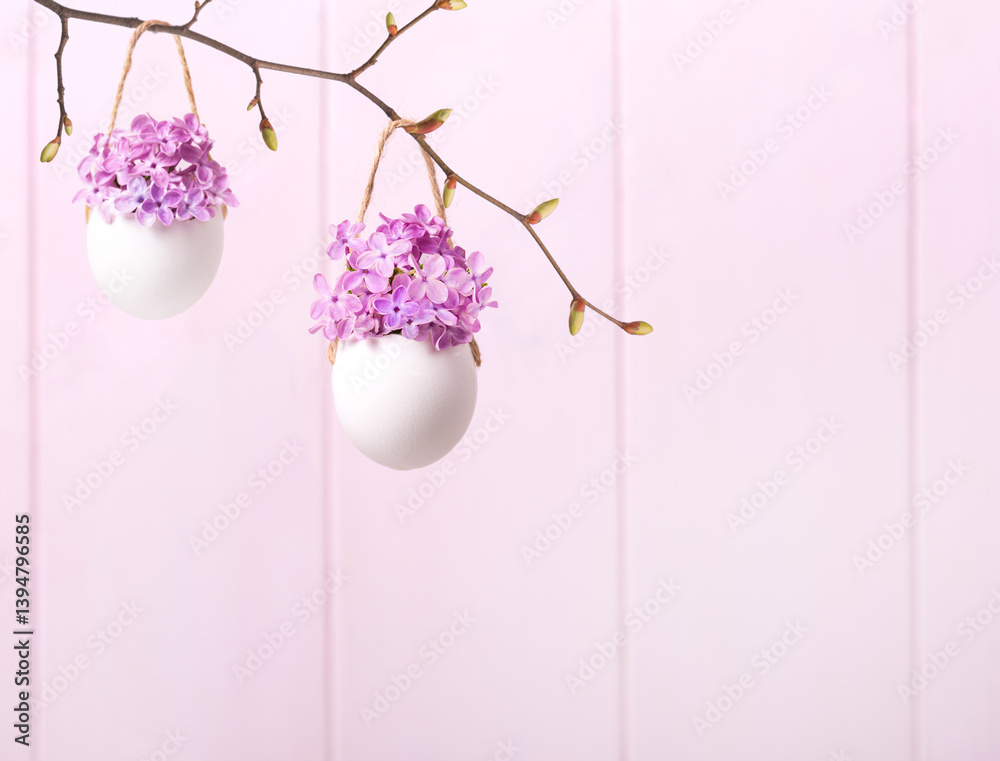 Lilac flowers (Syringa) in eggsshells against a light pink background. Easter decor.