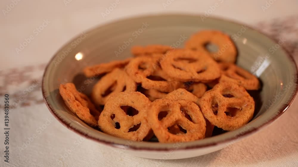 Close-up shot of a ceramic bowl filled with crispy mini pretzels on a light tablecloth. A perfect savory snack for parties or casual gatherings.
