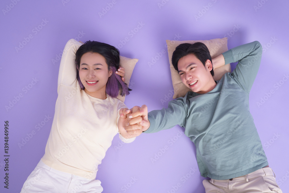 Obraz premium Happy couple relaxing together on a purple background holding hands and enjoying each other's company