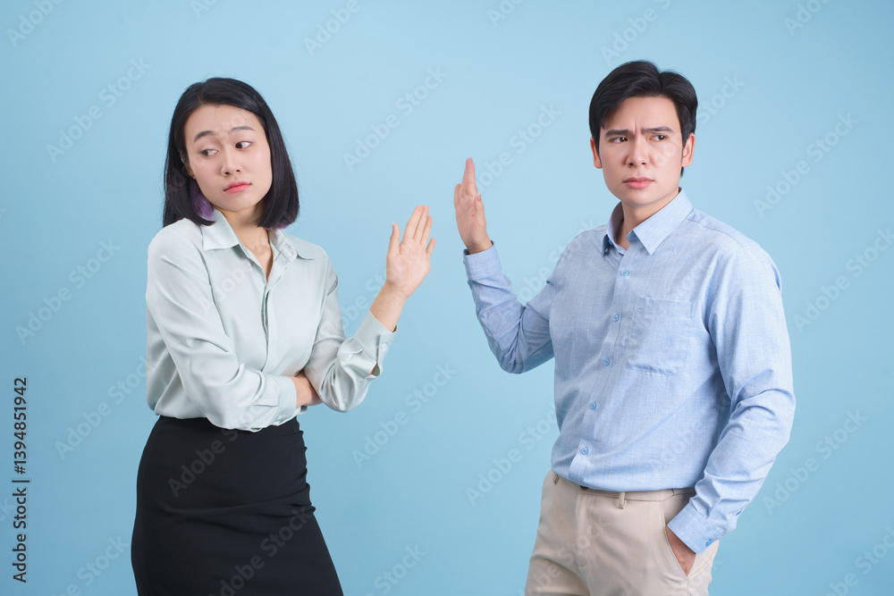 Conflicted emotions between a man and a woman against a plain blue background during an argument or disagreement Conflicted emotions between a man and a woman against a plain blue background during an argument or disagreement