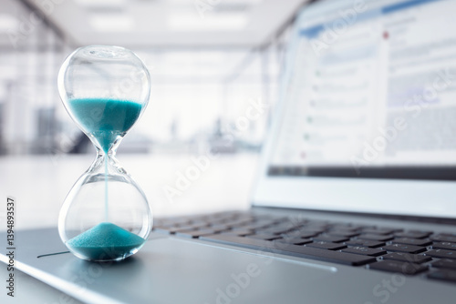 Hourglass on laptop computer keyboard concept for time management