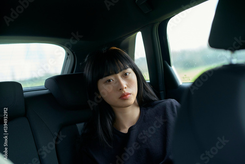 Woman with long black hair sitting in a car's backseat, looking out the window. Brandenburg, Germany photo
