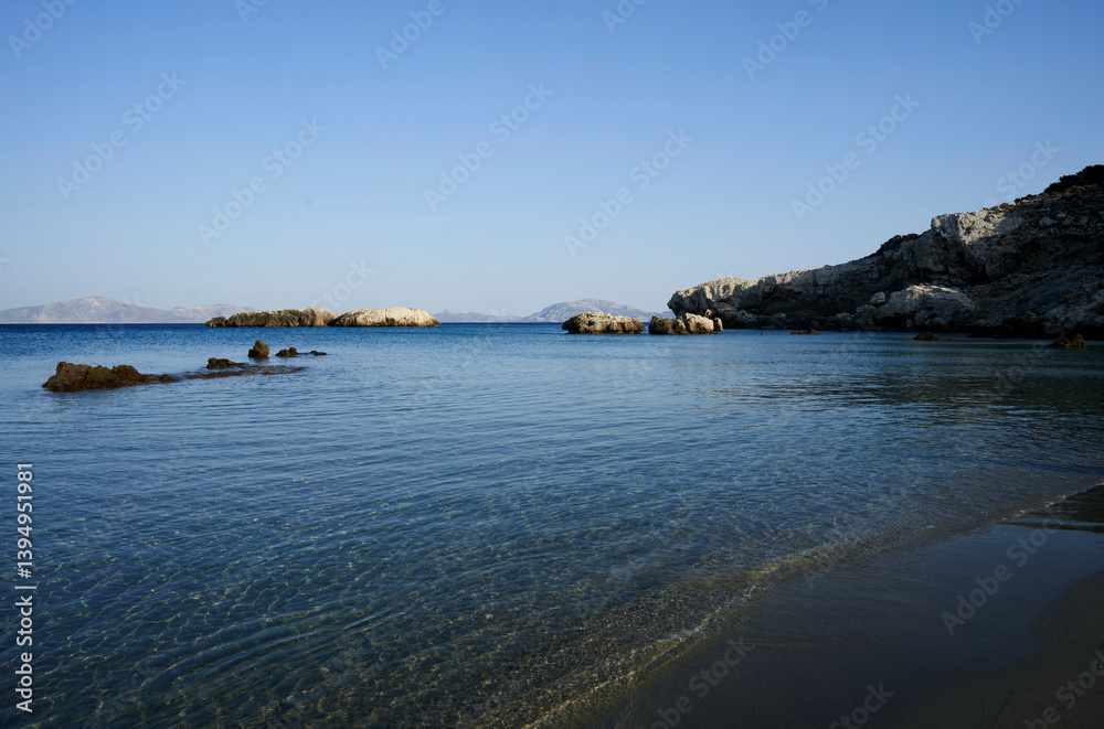 Tranquil coastal scene with clear blue water and rocky shoreline under a bright sky. Tranquil coastal scene with clear blue water and rocky shoreline under a bright sky.