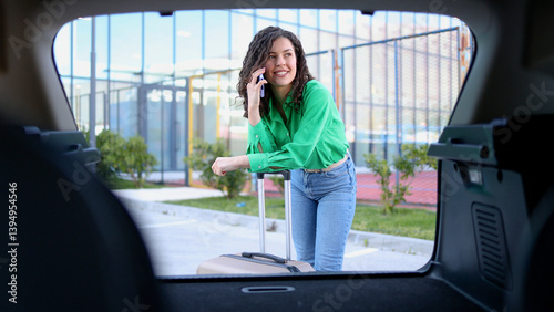 Wallpaper Mural Young woman chatting on her smartphone while leaning on her suitcase placed in the trunk of her car Torontodigital.ca