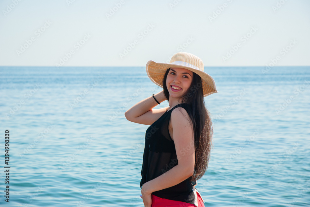 Woman enjoying a sunny day at the beach in a wide-brimmed hat. Happy summer days, travel and vacation concept Woman enjoying a sunny day at the beach in a wide-brimmed hat. Happy summer days, travel and vacation concept