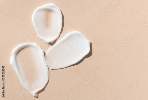 Cosmetic beige background with samples of cream, lotion, face wash, top view with copy space.