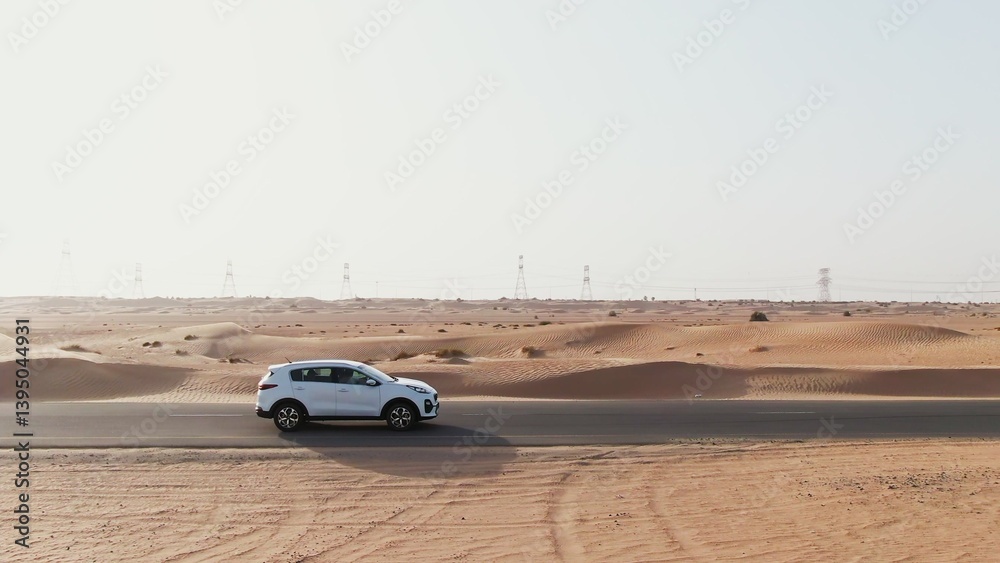 Vertical panning from a quadcopter. A white car is driving alone on a road in the desert. Aerial view of desert Vertical panning from a quadcopter. A white car is driving alone on a road in the desert. Aerial view of desert
