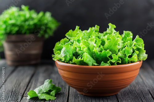 Fresh green salad in ceramic bowl, vibrant and healthy, showcasing crisp lettuce leaves on wooden table