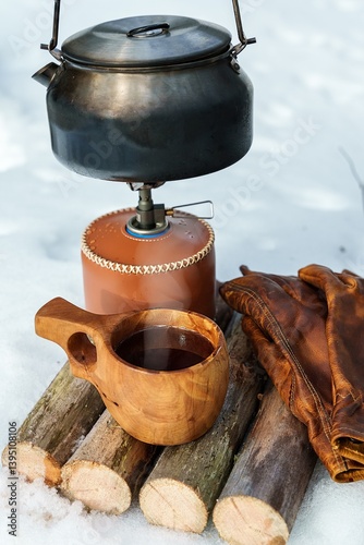 Warm coffee served in a traditional Scandinavian wooden cup. Brewing coffee on a gas stove during a winter hike.