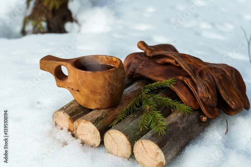 A wooden kuksa cup filled with steaming hot coffee. Coffee during a winter hike, embracing Scandinavian traditions.