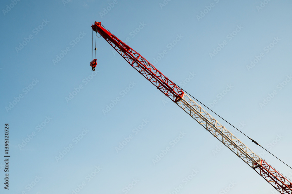 Red and white construction crane against clear blue sky Red and white construction crane against clear blue sky