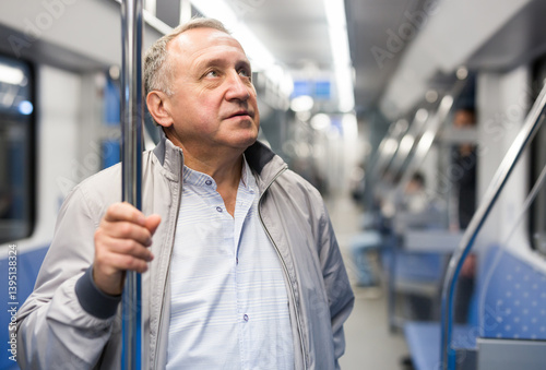 Portrait of senior positive man 60 year old in subway car
