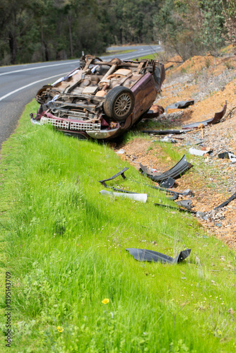 Crashed vehicle upside down on side of highway
