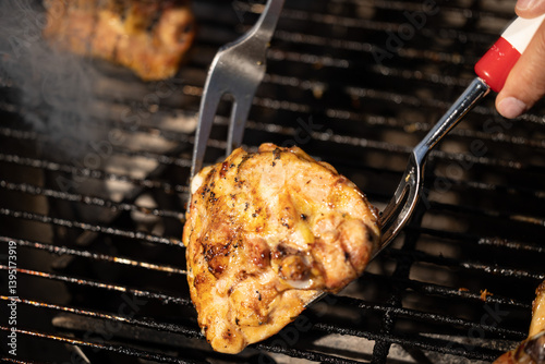 Obraz na płótnie pezzo di carne di pollo mentre viene girata e cucinata su una griglia w salonie