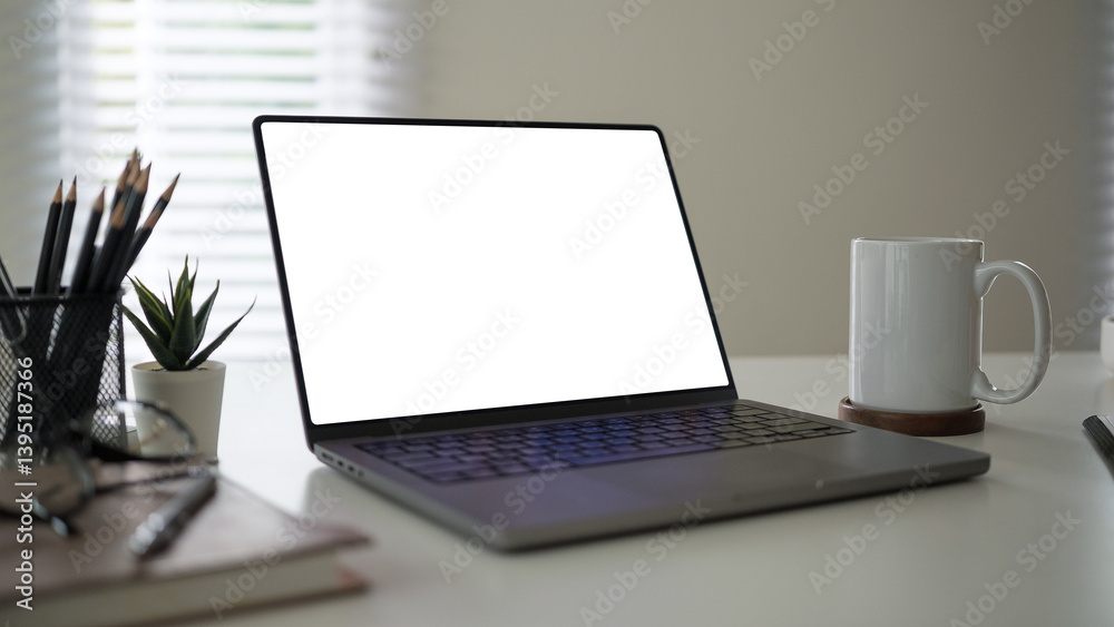 Fototapeta premium Modern desk setup featuring a laptop with a blank white screen, perfect for customization.