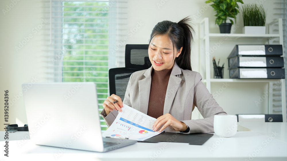 A confident young woman in business attire reviews colorful charts and data while seated at a clean, bright workspace. A confident young woman in business attire reviews colorful charts and data while seated at a clean, bright workspace.