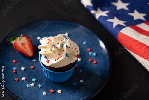 Obraz na płótnie Traditional American sweet cupcake with sugar sprinkles as stars and USA flag in blue plate on dark background. Dessert for Patriotic Independence Day 4th of july. Close up. w salonie