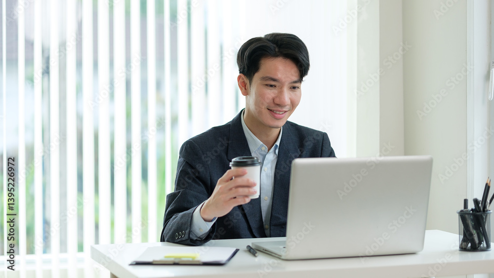 Business professional in formal attire engaged in a virtual meeting or webinar, sipping coffee and interacting with his laptop. Business professional in formal attire engaged in a virtual meeting or webinar, sipping coffee and interacting with his laptop.