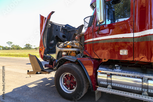 A red or maroon semi-trailer broken down with bonnet up.