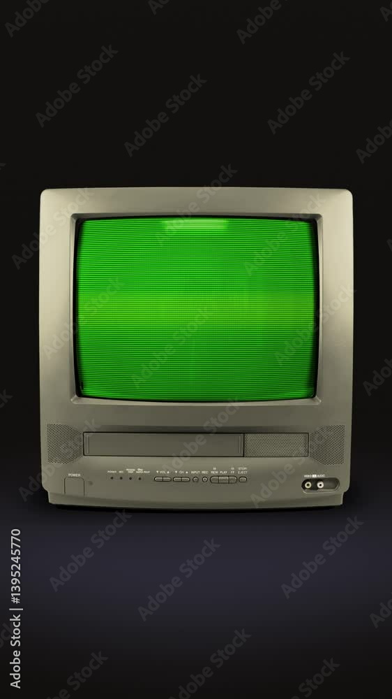Old grey TV on a black background with a green screen. TV from the 90s with chromakey. CRT screen of a vintage TV with flickering and interference. Looping animation. Vertical video. 9:16 format.