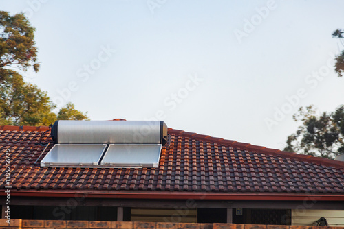 Solar panel and hot water heater on tilled roof of home