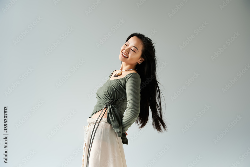 Young woman with long hair joyfully posing against a simple background in a stylish outfit