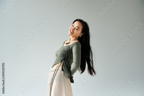 Obraz na płótnie Young woman with long hair joyfully posing against a simple background in a stylish outfit w salonie