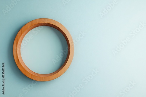 Obraz na płótnie A small round wooden frame with a smooth, matte finish, placed in the lower corner of a pale blue wall, creating an intriguing off-center composition. w salonie