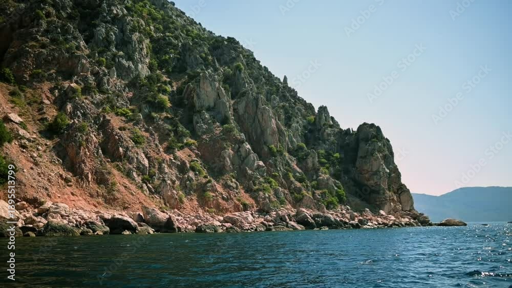 Majestic rocky cliff towering over deep blue sea. Sunlight illuminates cliff's rugged texture, highlighting transition from rocky terrain to tranquil ocean. Nature's raw beauty captured in a tranquil. Majestic rocky cliff towering over deep blue sea. Sunlight illuminates cliff's rugged texture, highlighting transition from rocky terrain to tranquil ocean. Nature's raw beauty captured in a tranquil.