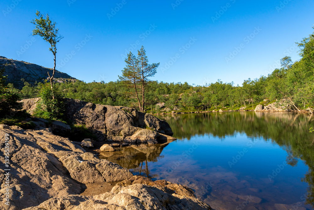 Pristine Lake View with Rocky Shoreline and Trees in the Middle of Preikestolen Hiking Trail, Stavanger, Norway, July 2018