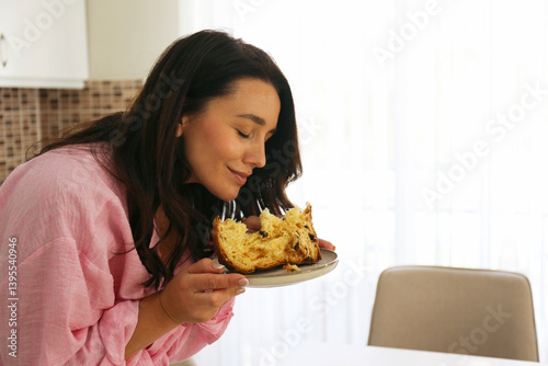 Brunette woman enjoying her panettone cake on Easter Sunday. Copy space, background.