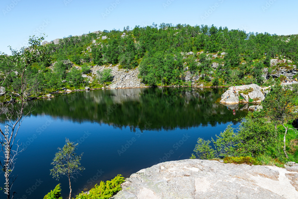 Scenic Mountain Lake with Lush Vegetation and Reflection Under Clear Blue Sky on Preikestolen Hiking Trail, Stavanger, Norway, July 2018