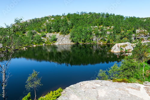 Obraz na płótnie Scenic Mountain Lake with Lush Vegetation and Reflection Under Clear Blue Sky on Preikestolen Hiking Trail, Stavanger, Norway, July 2018 w salonie