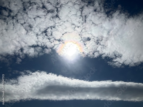 Blue sunny sky with Stratocumulus volutus, Roll clouds and pearl colors, optical phenomenon Iridescence on Altocumulus around sun. Topics: weather, meteorology, nature, airspace