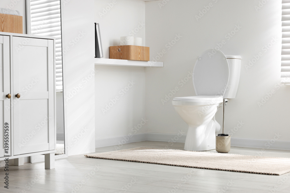 Toilet and brush near white wall in bathroom