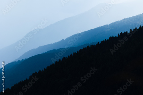 Obraz na płótnie sagome di pendii di varie montagne in controluce, colorate da sfumature di blu ed avvolte nella foschia w salonie