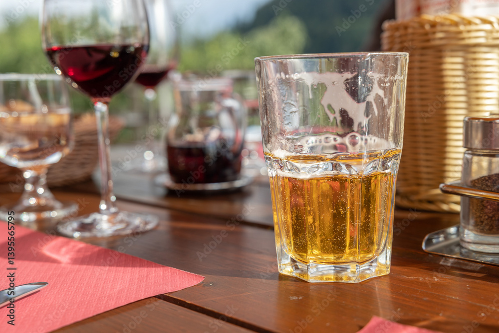 tavolo di legno, al ristorante, apparecchiato con vari bicchieri riempiti con vino ed altre bevande, e dei cestini per il pane e grissini, di giorno