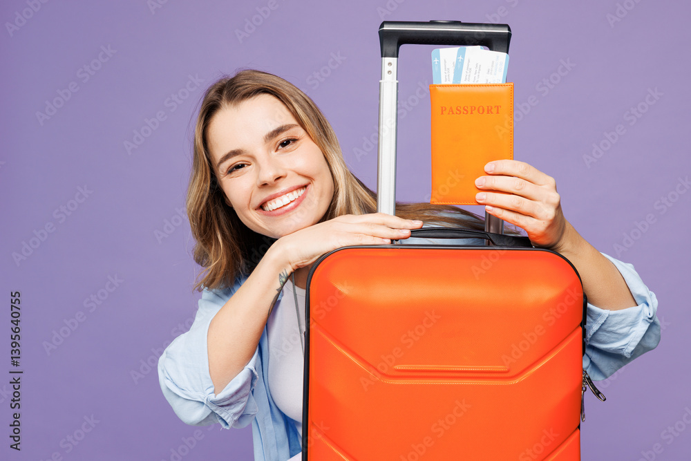Close up happy traveler woman wear blue clothes hold passport ticket suitcase bag isolated on plain purple background. Tourist travel abroad in free time rest getaway. Air flight trip journey concept.