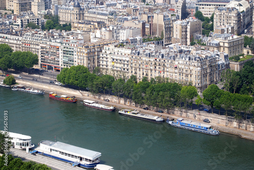 View of the Seine embankment and moored pleasure boats from the top of the Eiffel Tower on a bright sunny day.