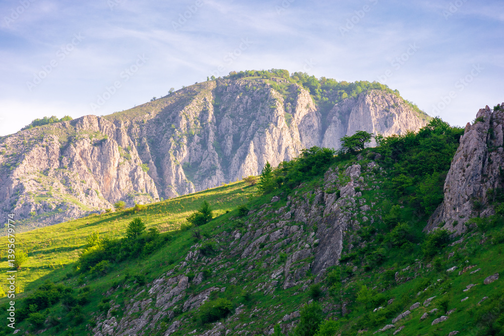 mountain landscape of romania in springtime. outdoor adventure. rock formation and grassy hill in morning light. scenery in valisoarei valley. travel europe