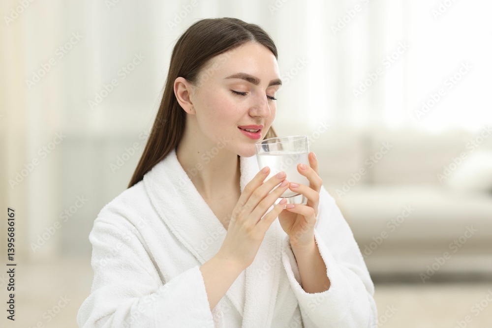 Smiling woman with glass of collagen water on blurred background Smiling woman with glass of collagen water on blurred background