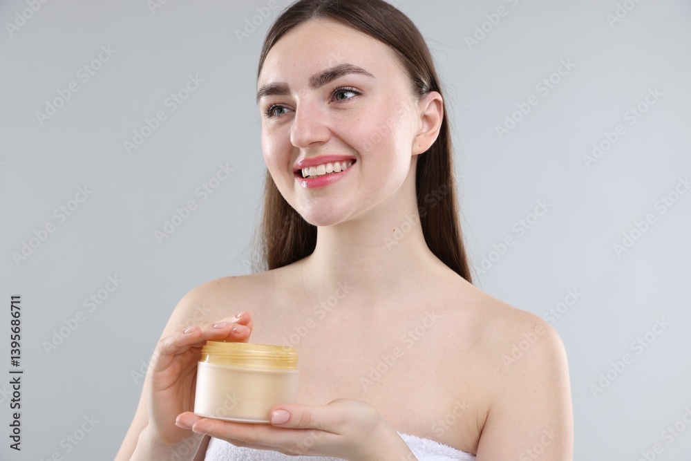 Smiling woman with jar of collagen cream on grey background