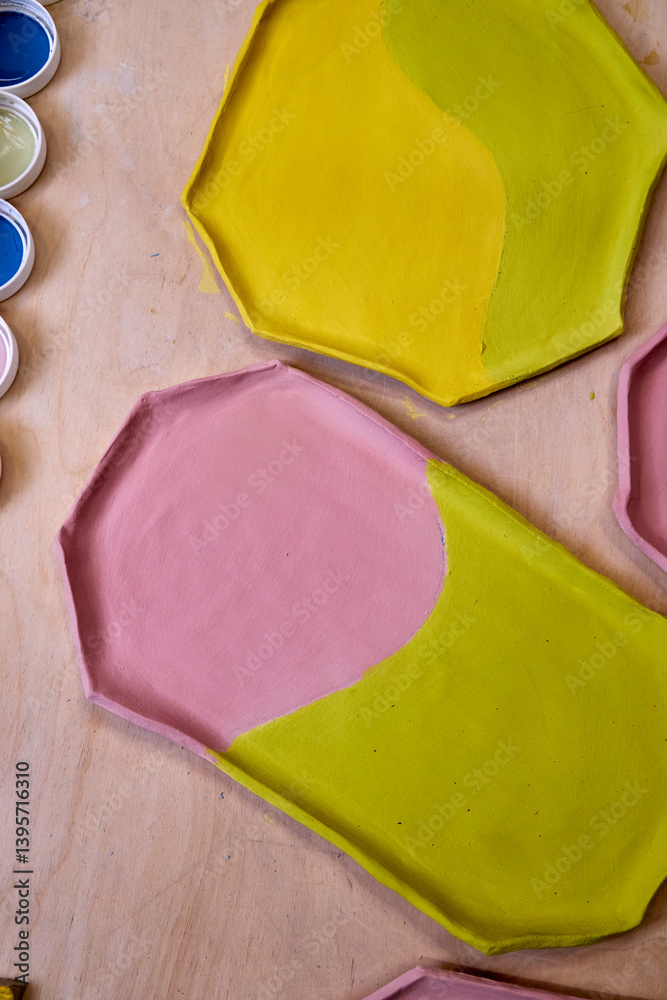 top view of handmade clay plates covered with colored glazes and glaze jars, ready for firing top view of handmade clay plates covered with colored glazes and glaze jars, ready for firing