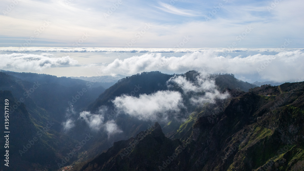 Naklejka premium Majestic mountain range framed by fluffy clouds and a serene horizon at dusk